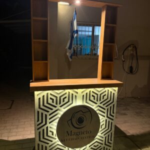עמדת בר מתפרקת ברוחב 120 ס"מ עם חזית דמוי שיש בחיתוך CNC גיאומטרי, משטח עץ וספרייה עליונה מוארת לתצוגת מוצרים