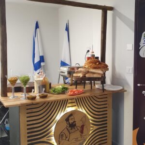 עמדת שף 120 ס"מ מעץ עם תליה עליונה מקורות אקליפטוס ולוגו מואר בחזית, ערוכה עם לחמים, ירקות ורטבים באירוע