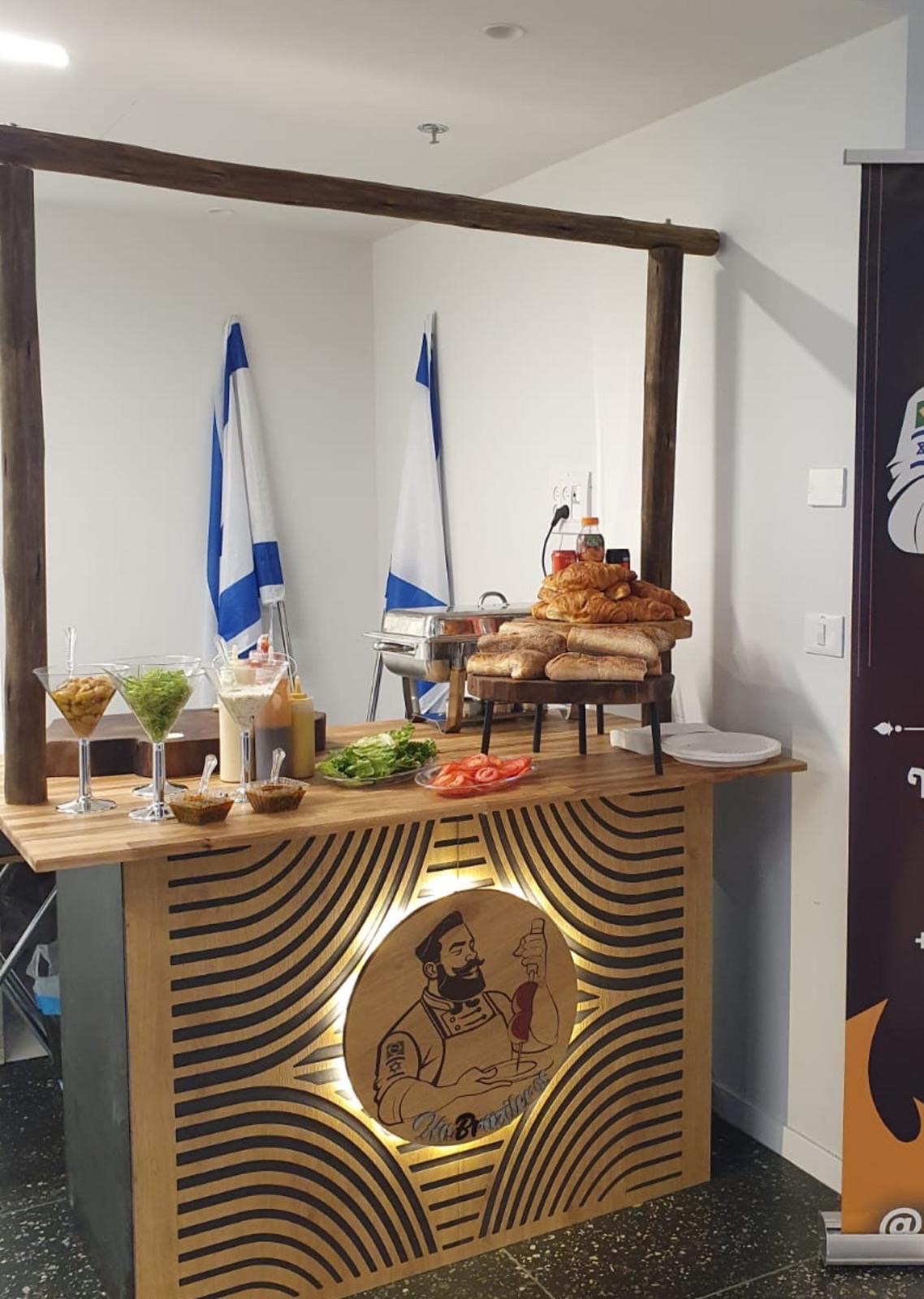 עמדת שף 120 ס"מ מעץ עם תליה עליונה מקורות אקליפטוס ולוגו מואר בחזית, ערוכה עם לחמים, ירקות ורטבים באירוע