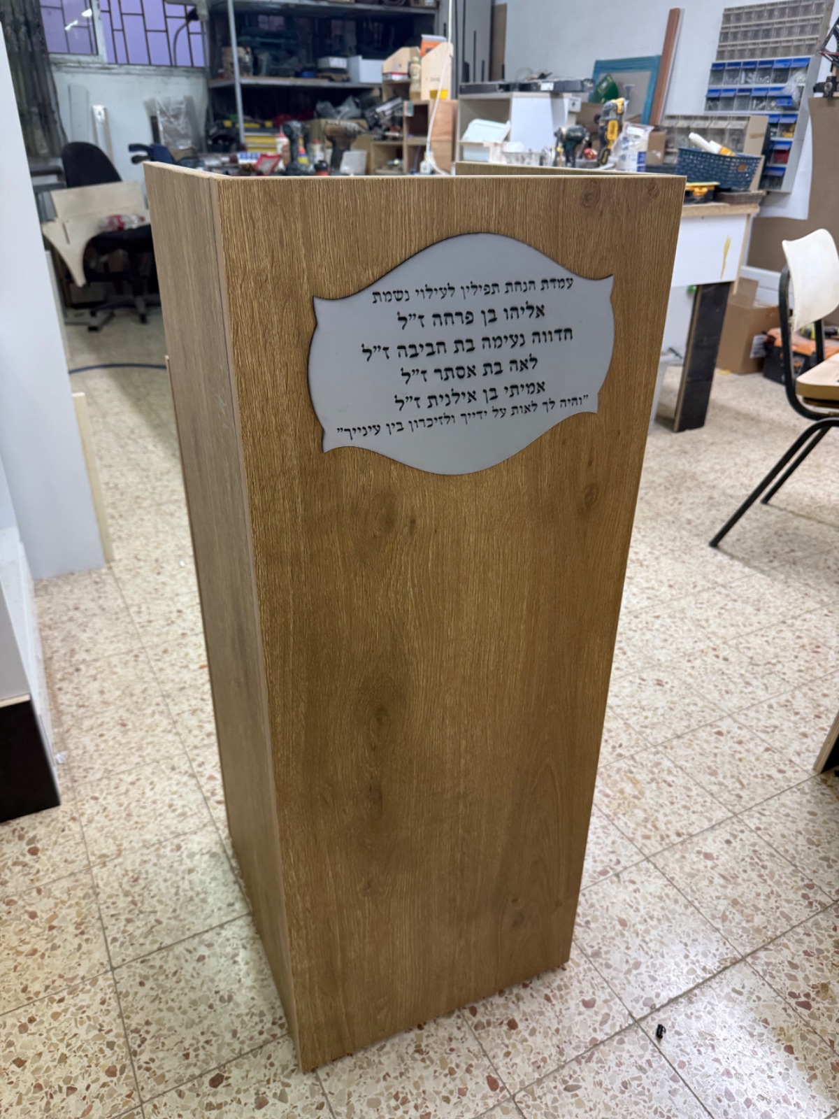 עמדת הנחת תפילין מעץ אלון עם שלט הנצחה בצורת מגילה