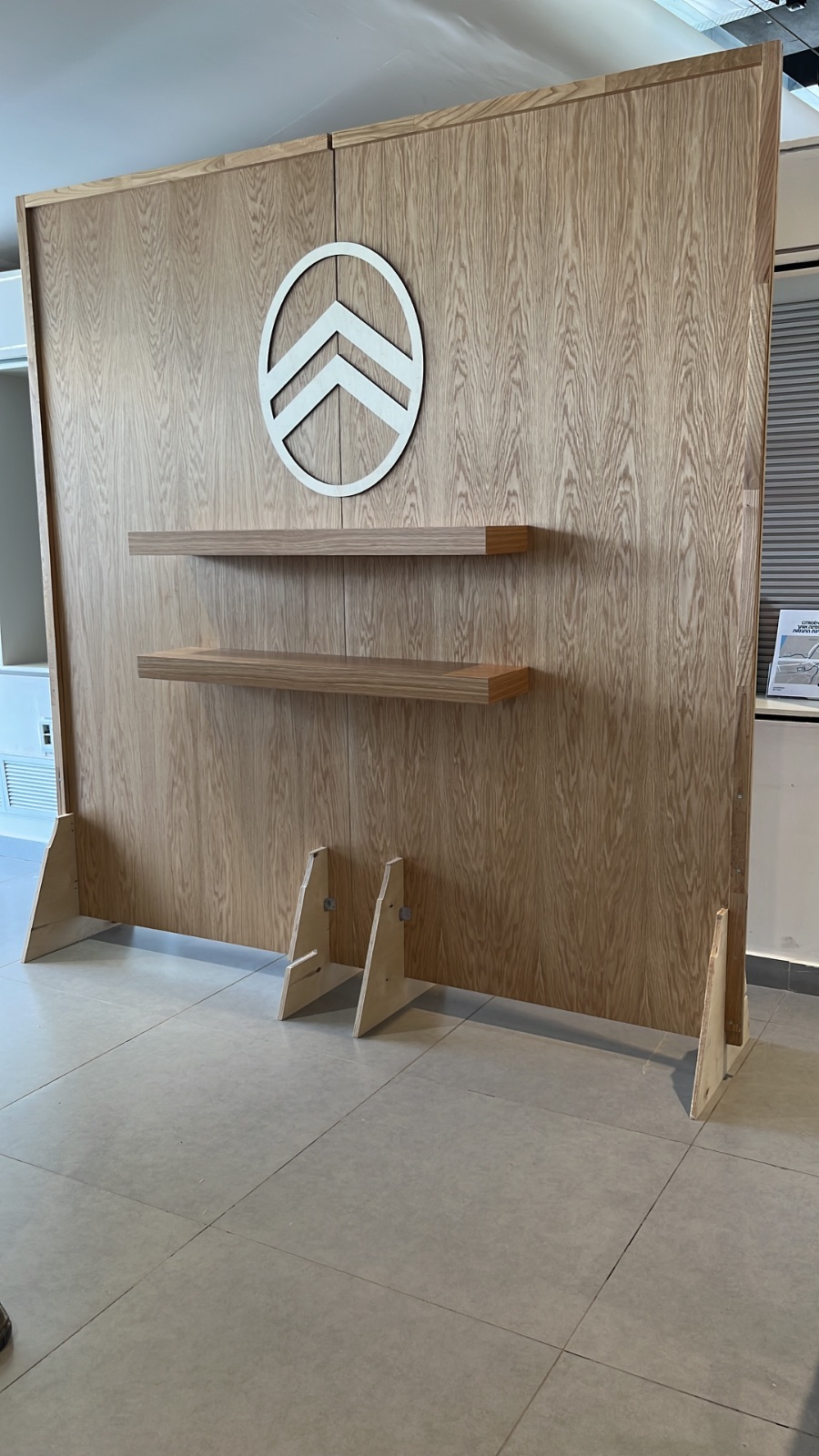 קיר תצוגה לאירועים מעץ אלון עם לוגו מרכזי ושני מדפים מתפרקים